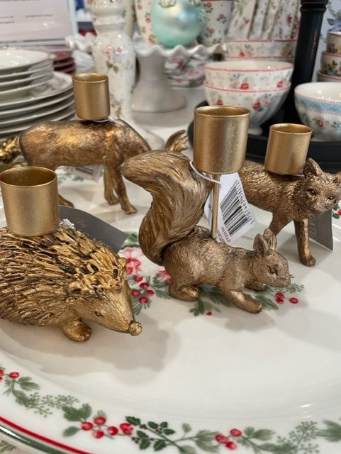 Set of four whimsical animal candle holders in gold, featuring a hedgehog, squirrel, fox, and deer.