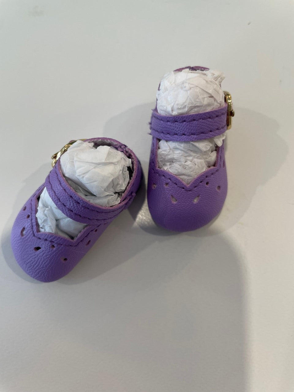 Purple baby shoes made from soft leather with decorative cutouts and adjustable strap for comfort.
