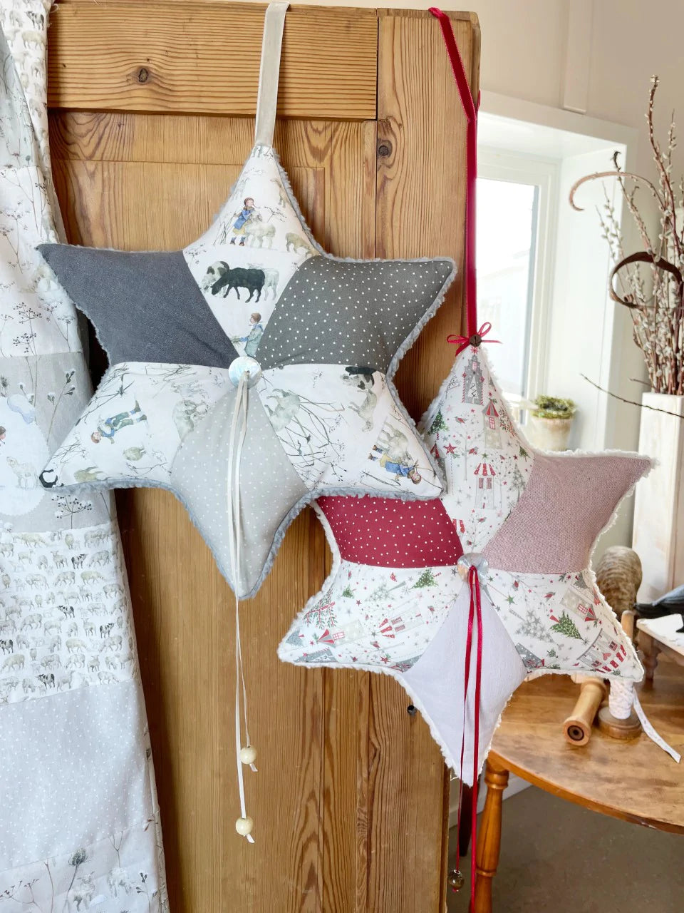 Two decorative star pillows in gray and red, featuring winter-themed prints and soft cotton material.